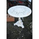 A CAST IRON WHITE PAINTED GARDEN TABLE with pierced detailed top, diameter 66cm, on top of a