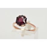 A YELLOW METAL GARNET RING, designed with a double four claw set, hexagonal cut garnet, tapered