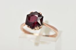 A YELLOW METAL GARNET RING, designed with a double four claw set, hexagonal cut garnet, tapered