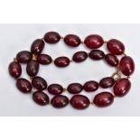 A CHERRY AMBER BAKELITE BEAD NECKLACE, a single row of graduated oval beads, largest measuring