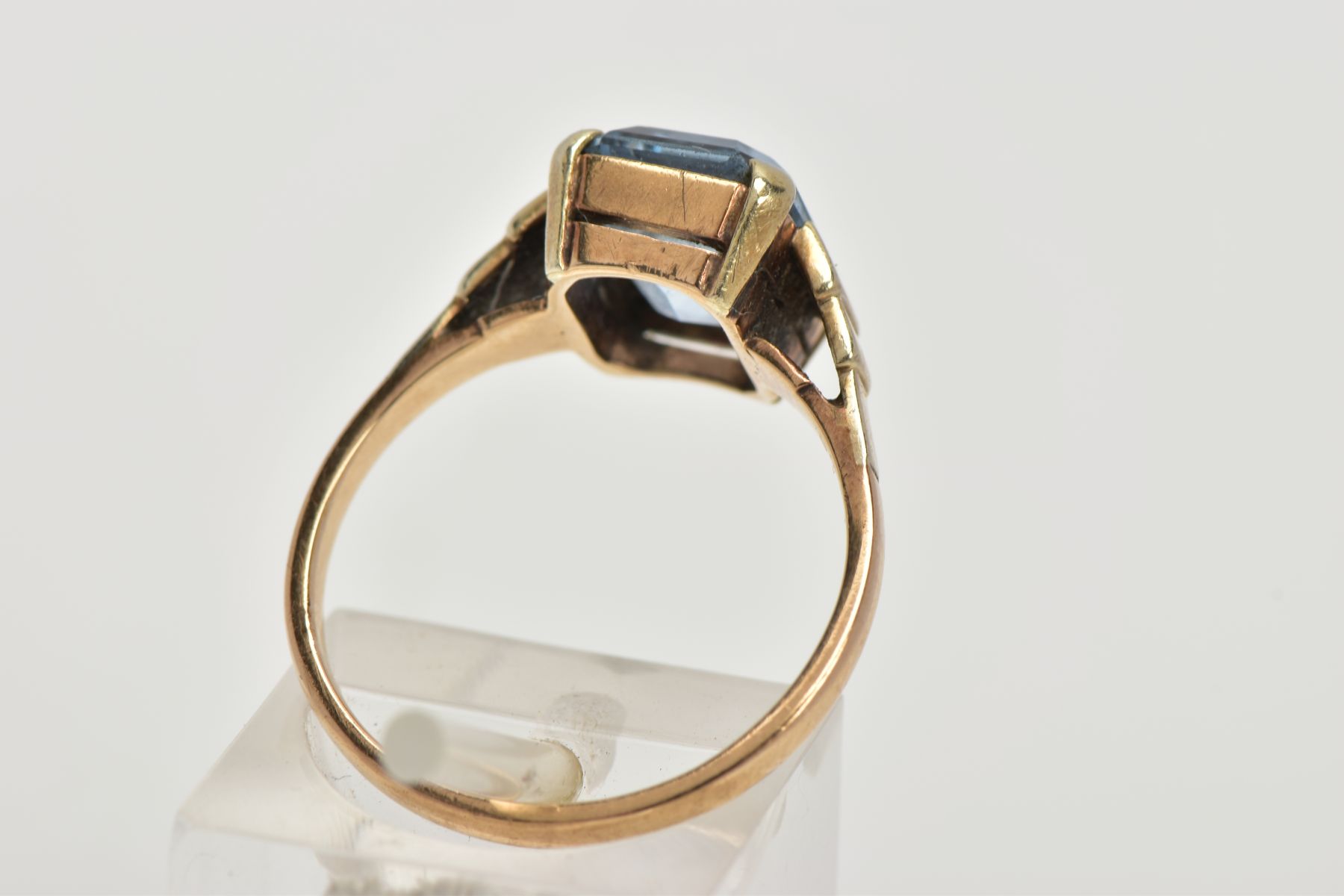 A YELLOW METAL RING, designed with an emerald cut pale blue stone assessed as synthetic spinel, step - Image 3 of 4