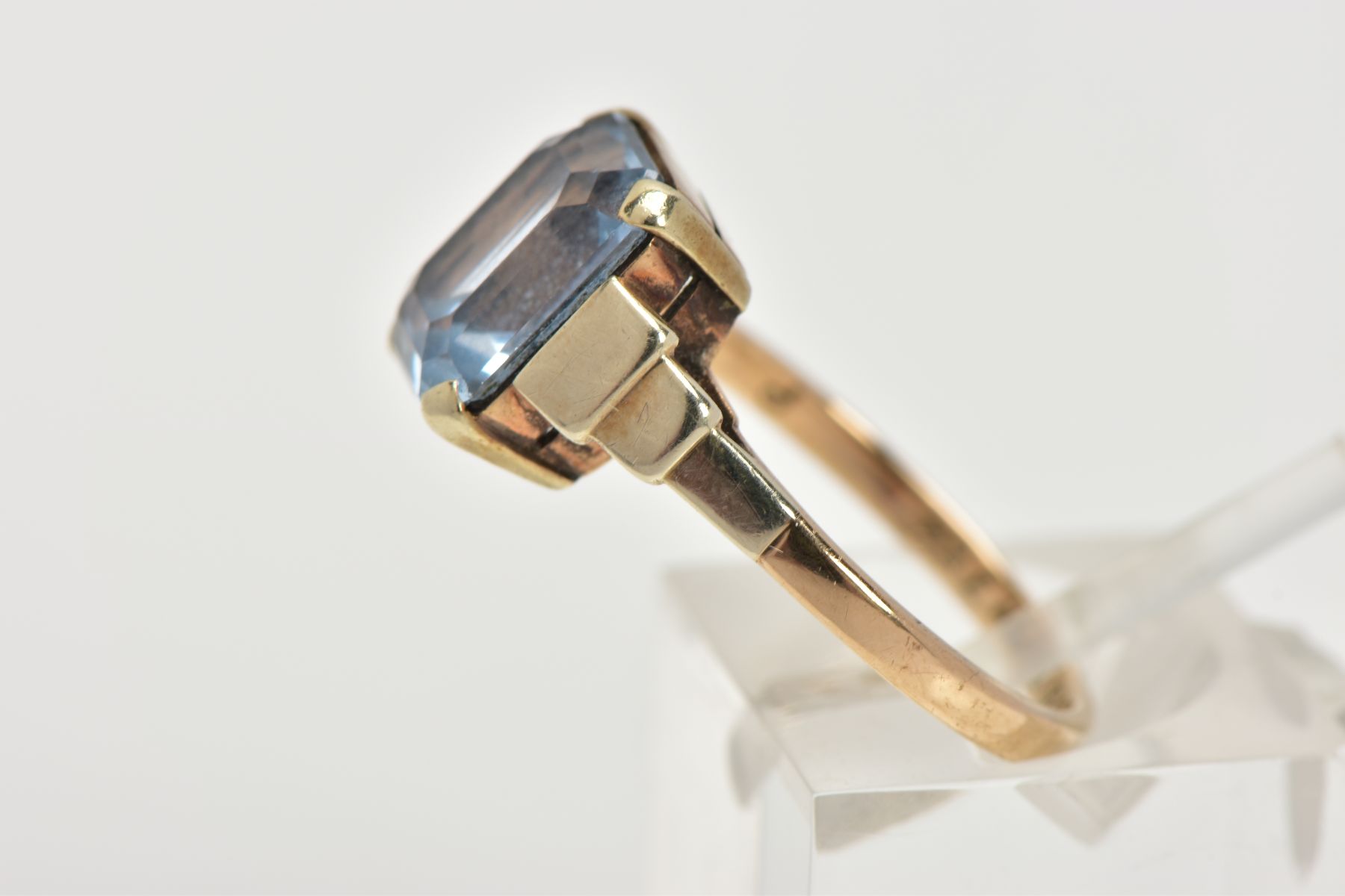 A YELLOW METAL RING, designed with an emerald cut pale blue stone assessed as synthetic spinel, step - Image 2 of 4