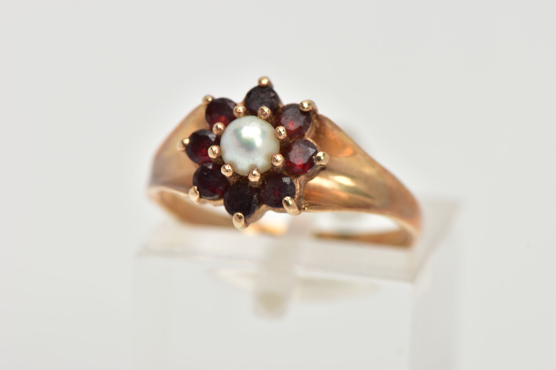 A 9CT GOLD GARNET AND PEARL CLUSTER RING, centring on a single cultured pearl, measuring