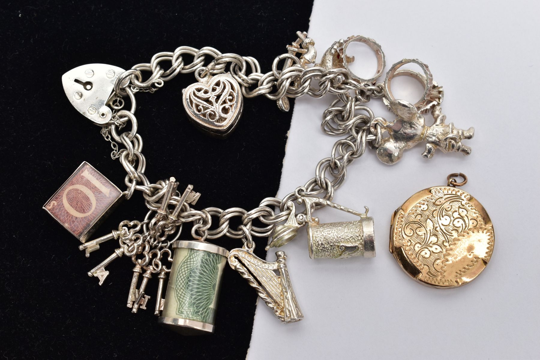 A SILVER CHARM BRACELET AND A LOCKET, the double curb link bracelet, some links stamped with a