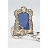 A SILVER PHOTO FRAME, TEASPOON AND A MAGNIFYING GLASS, the photo frame of a wavy rectangular form,