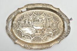 AN INDIAN WHITE METAL PIERCED TRAY, of an oval form, embossed city scene to the centre, with