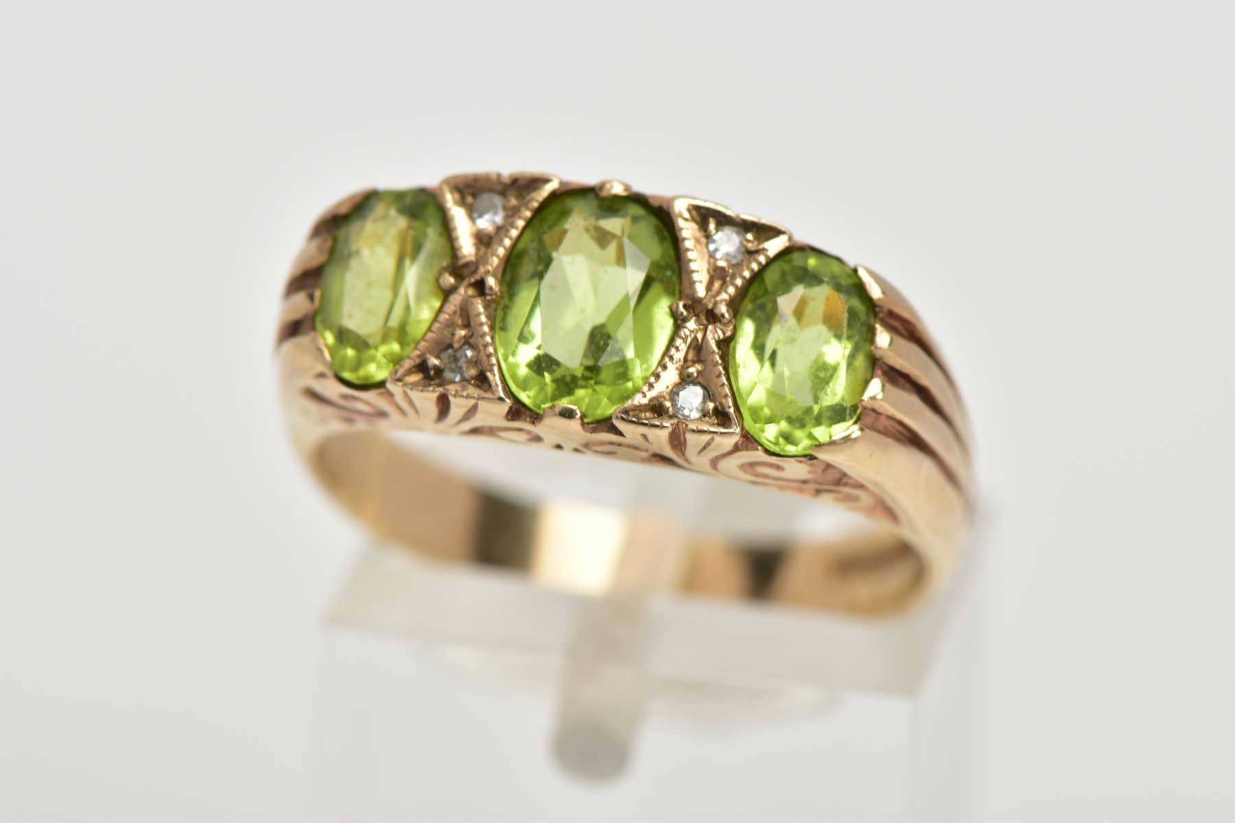 A MODERN 9CT GOLD SEVEN STONE DRESS RING, designed with three oval cut peridots, interspaced with