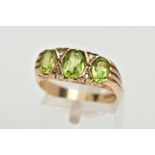 A MODERN 9CT GOLD SEVEN STONE DRESS RING, designed with three oval cut peridots, interspaced with