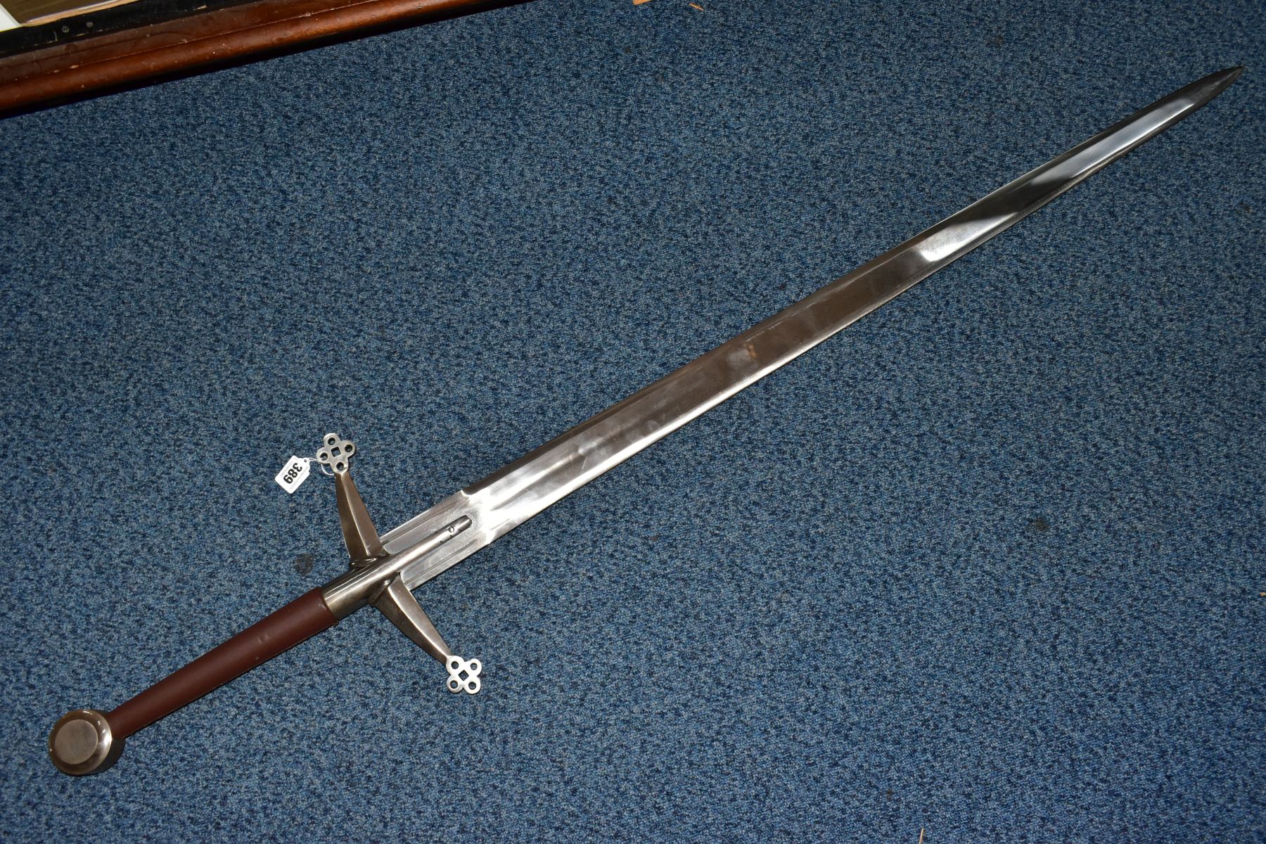 A LARGE REPRODUCTION SWORD, with leather grip, pierced cross guard, sharpened blade, length 142cm (