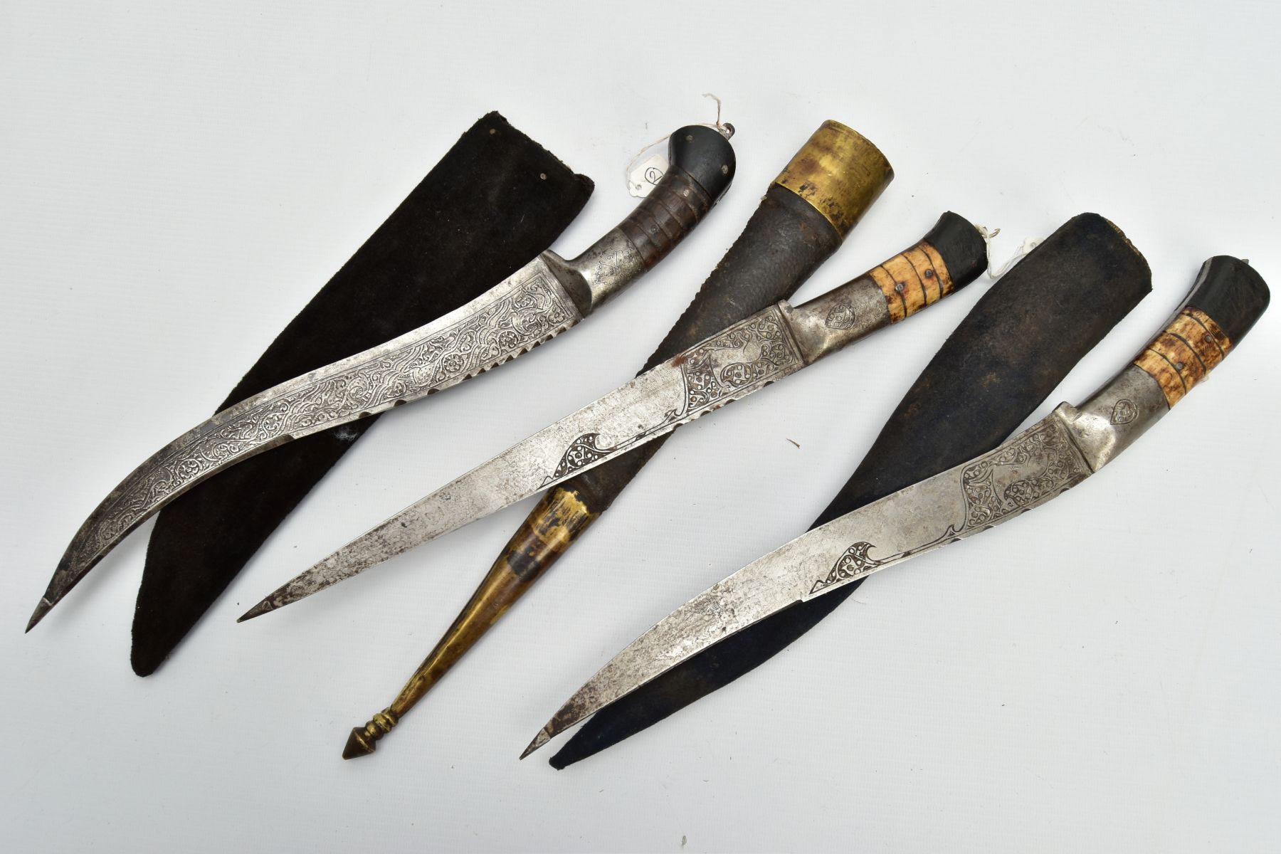 THREE INDIAN/ASIAN short daggers all with skin covered wooden scabbards, one with straight blade