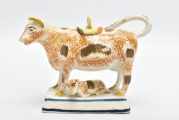 AN EARLY 19TH CENTURY PEARLWARE COW CREAMER, modelled with a recumbent calf below its mother, sponge