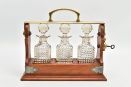 AN EARLY 20TH CENTURY MINIATURE THREE BOTTLE WALNUT AND BRASS TANTALUS, of rectangular outline,