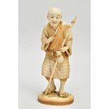 A JAPANESE MEIJI PERIOD IVORY OKIMONO, of a man standing holding a staff, on an oval base, the