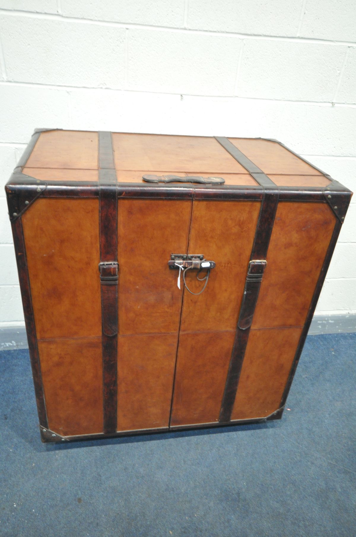 A BROWN LEATHER WRAPPED COCKTAIL CABINET, possibly made by 'Coach house', the two door enclosing