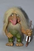 A NORWEGIAN NYFORM TROLL, with hair, beard and furry tail, carrying a stick, height 22cm (