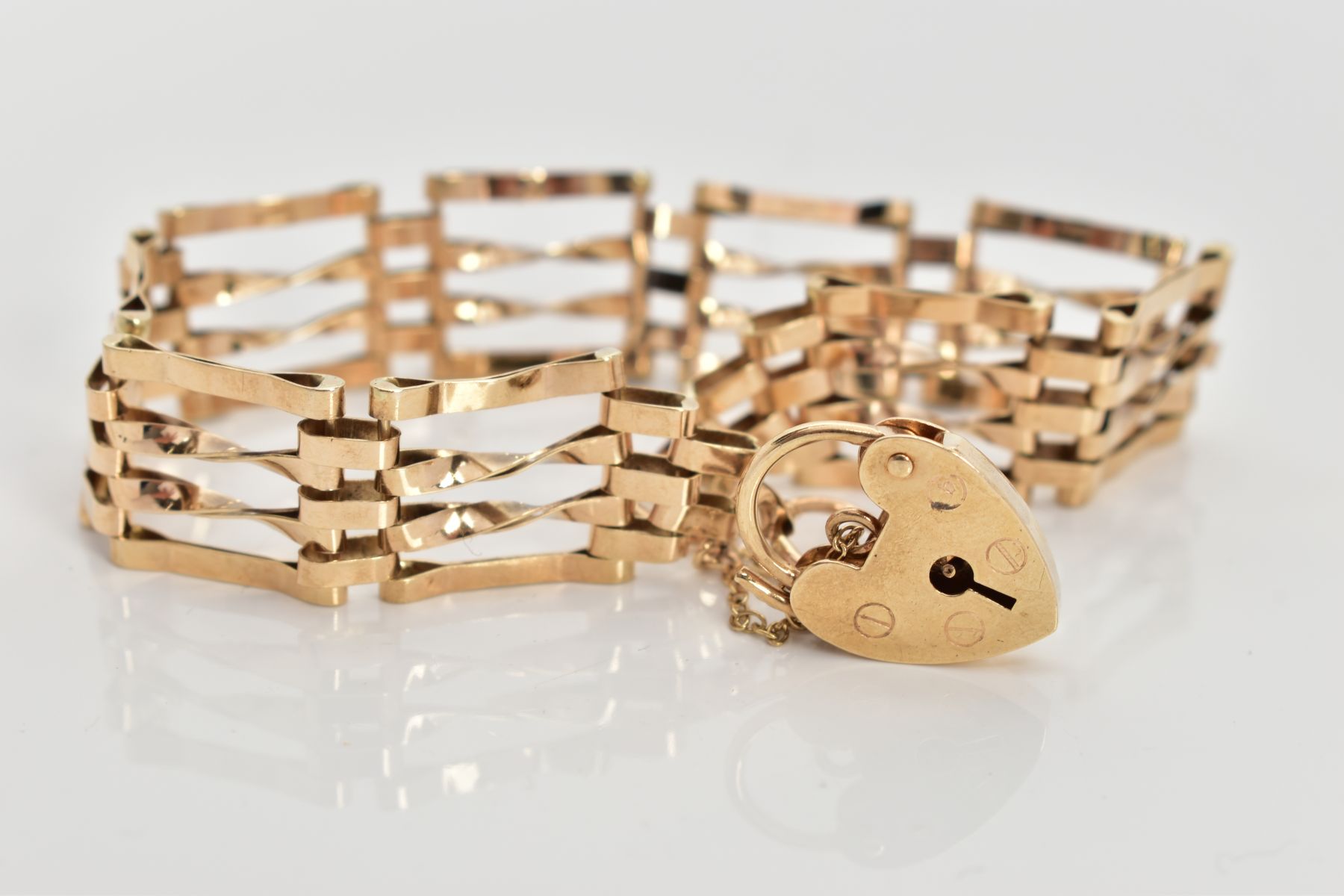 A 9CT GOLD GATE BRACELET, four bar polished yellow gold gate bracelet, fitted with a heart padlock