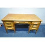 A MID 20TH CENTURY OAK KNEE HOLE DESK, with seven various drawers and two brushing slides, width