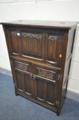 AN OLD CHARM OAK LINENFOLD COCKTAIL CABINET, the hinged top and fall front with a mirror back and