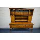 A GOOD REPRODUCTION OAK DRESSER, the top with an arrangement of shelves and two cupboard doors, over