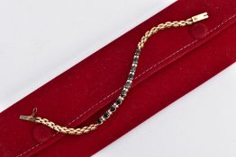 A YELLOW METAL SAPPHIRE AND DIAMOND LINE BRACELET, designed with a row of ten oval cut deep blue