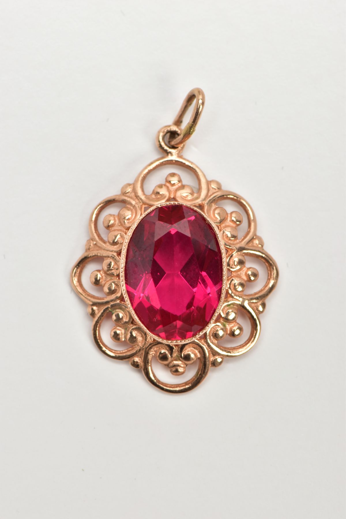 A YELLOW METAL SYNTHETIC RUBY PENDANT, designed with a central oval cut synthetic ruby,