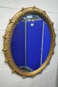 A LATE 20TH CENTURY GILT FRAMED OVAL WALL MIRROR, with foliate and rose head decorations, 97cm x