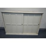 A LATE 19TH CENTURY LARGE CREAM PAINTED PINE SCHOOL CUPBOARD, with two panelled sliding doors,