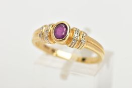A YELLOW METAL RUBY AND DIAMOND DRESS RING, centring on a bezel set oval cut ruby, flanked with