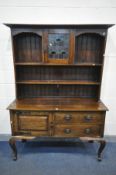 AN ARTS AND CRAFTS OAK DRESSER, two plate rack sections flanking a central lead glazed cupboard, the