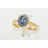 AN 18CT GOLD CLUSTER RING, centring on an oval cut blue stone assessed as sapphire and sixteen