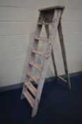 A VINTAGE SET OF WOODEN STEP LADDERS, deep when closed 41cm at widest point (condition:- distressed,