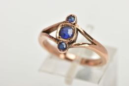 A THREE STONE RING, three graduated circular cut blue stones, within a rose gold tone mount,