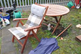 A MODERN NOVA HARDWOOD CIRCULAR FOLDING GARDEN TABLE 130 cm in diameter, a parasol and a Hardwood