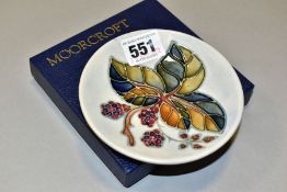 A BOXED MOORCROFT POTTERY CIRCULAR PIN DISH DECORATED WITH A BLACKBERRIES AND BRAMBLE DESIGN, on a