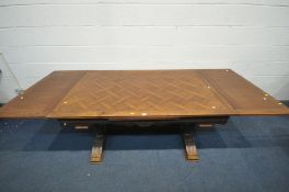 A FRENCH OAK DRAW LEAF DINING TABLE, with a parquetry decorated top, on twin legs with acorn