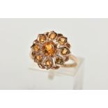 A 9CT GOLD CLUSTER RING, in the form of a flower, set with a central circular cut orange stone