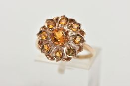 A 9CT GOLD CLUSTER RING, in the form of a flower, set with a central circular cut orange stone