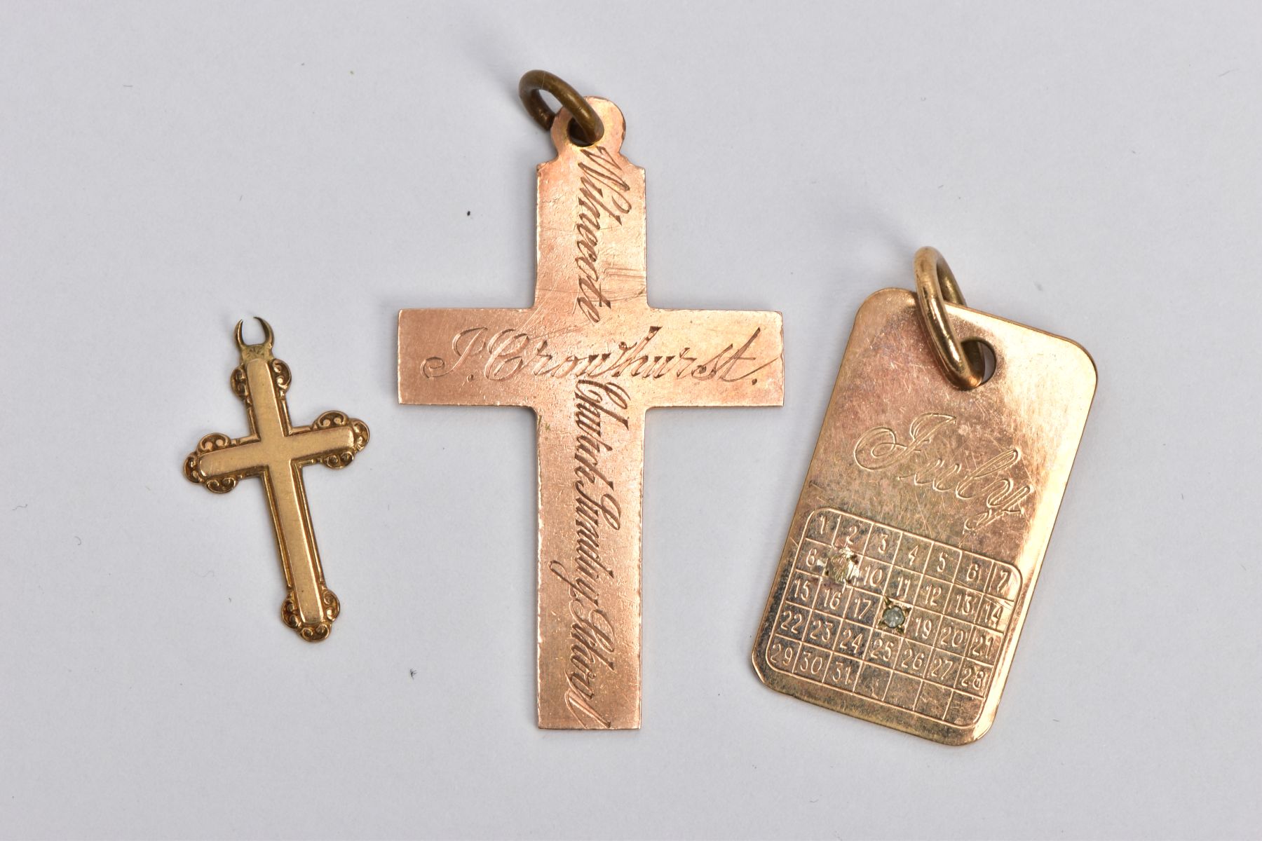 THREE 9CT GOLD PENDANTS, the first a rose gold cross pendant with personal engravings all round,