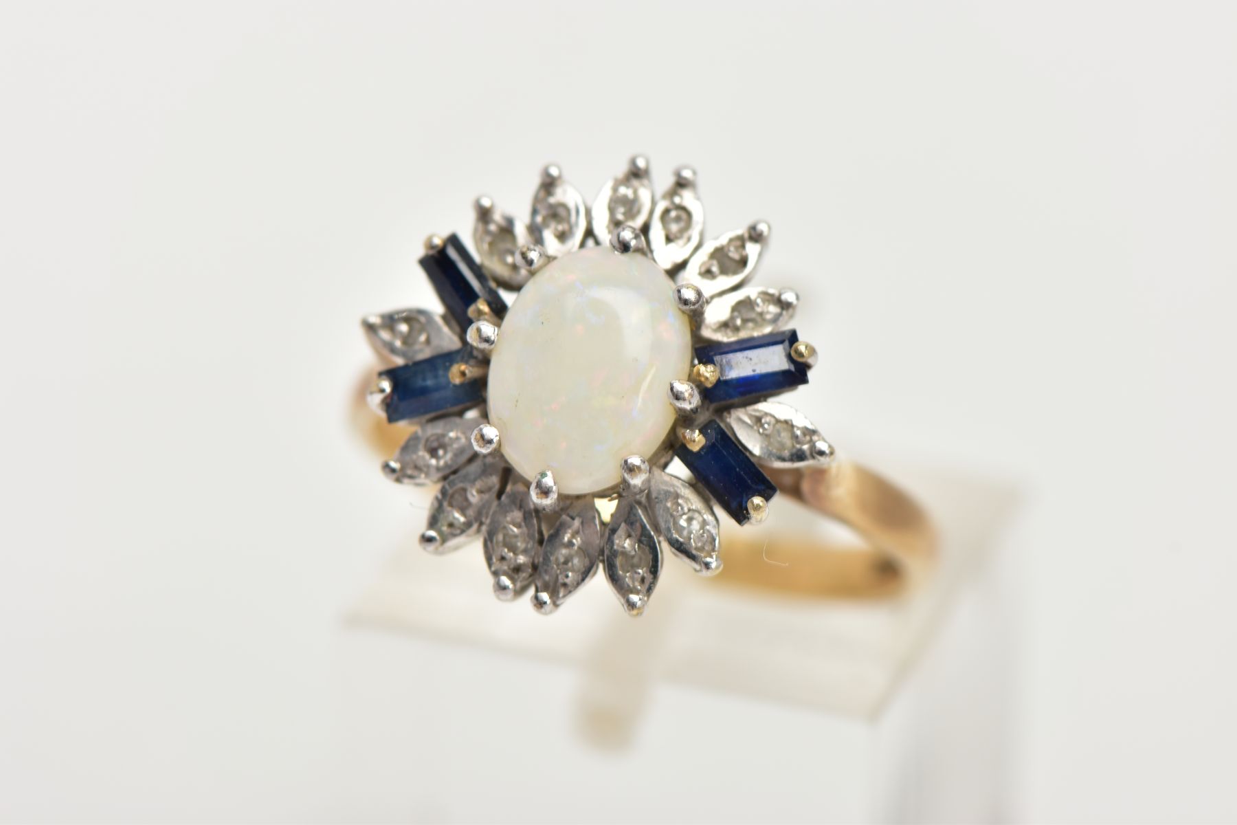 A 9CT GOLD OPAL CLUSTER RING, designed with a central oval cut opal cabochon, flanked with four