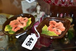 TWO SMALL MOORCROFT PIN DISHES, with coral hibiscus on a brown ground, one oval, length 8.2cm and