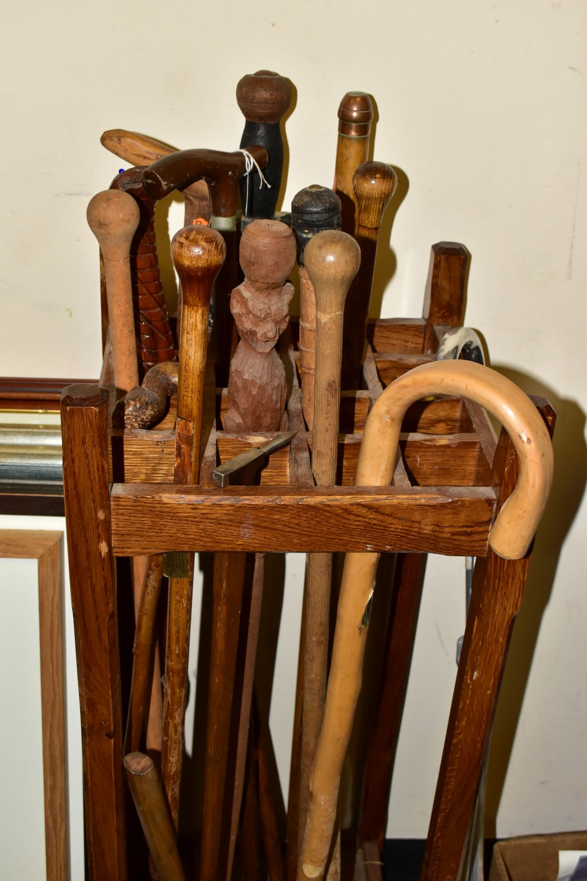 A WOODEN STICK STAND AND CONTENTS, the stand with sixteen small divisions, width and depth 33.5cm