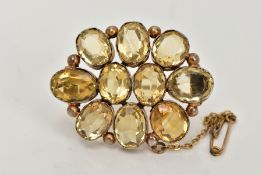 A GILT CITRINE BROOCH, of an oval form set with ten oval cut citrines, each collet mounted with