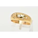 A YELLOW METAL RING, wide band set with seven circular cut colourless cubic zirconia stones each
