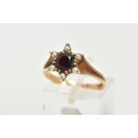 A 9CT GOLD GARNET AND SEED PEARL CLUSTER RING, centring on a circular cut garnet double claw set