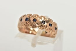 A 9CT GOLD SAPPHIRE RING, a wide gold band ring with a floral engraved design, flush set with