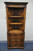 A SOLID OAK OPEN CORNER CUPBOARD, with two fixed shelves, over a single fielded panel cupboard door,