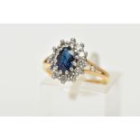 AN 18CT GOLD SAPPHIRE CLUSTER RING, centring on an oval cut deep blue sapphire, claw set within a