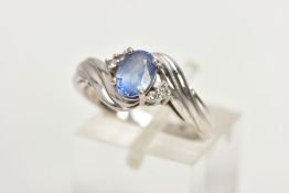 AN 18CT WHITE GOLD RING, designed with a central four claw set, oval cut light blue stone, flanked