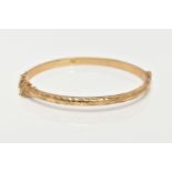A 9CT GOLD HINGED BANGLE, diamond cut pattern to one side, plain polished to the other, sliding