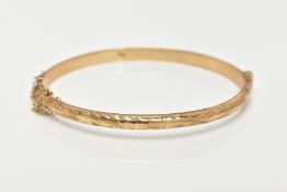 A 9CT GOLD HINGED BANGLE, diamond cut pattern to one side, plain polished to the other, sliding